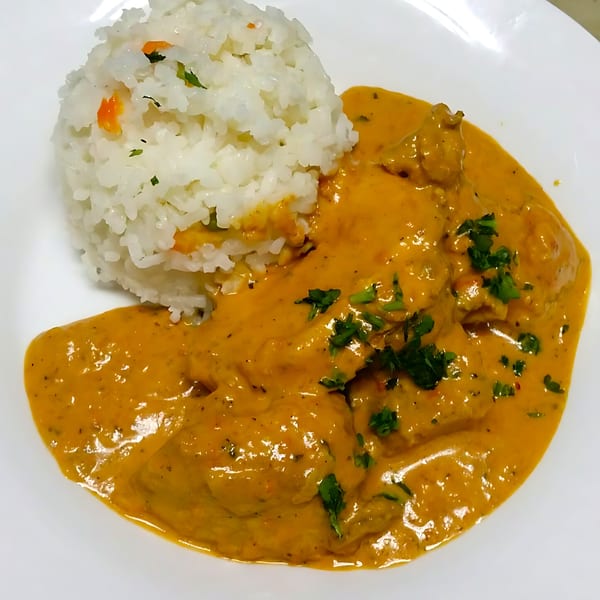 Chicken curry with rice, garnished with parsley, served on a white plate at Blue Olive Grill.