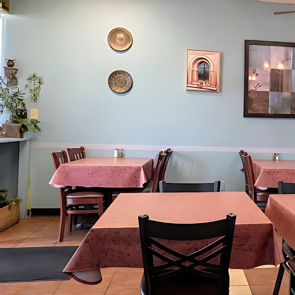 Dining room at Blue Olive Grill with tables set with pink tablecloths and Mediterranean-themed wall decor.