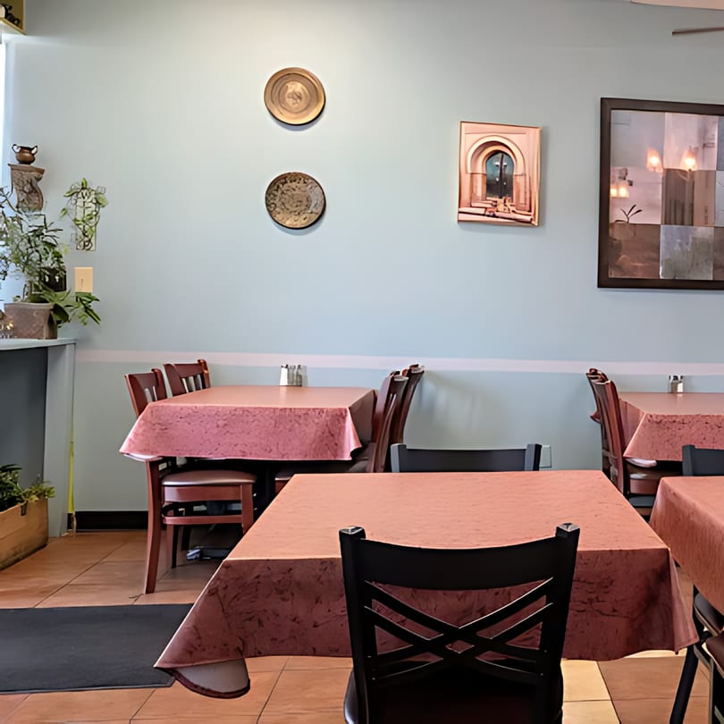 Dining room at Blue Olive Grill with tables set with pink tablecloths and Mediterranean-themed wall decor.