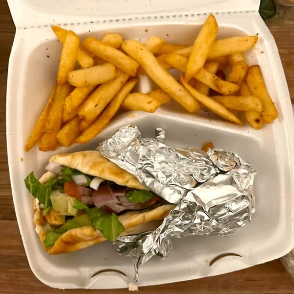 Blue Olive Grill's Mediterranean pita sandwich with fries in a white takeout container.