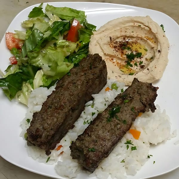Blue Olive Grill's Mediterranean plate with two meat kebabs, rice, hummus, and a side salad.